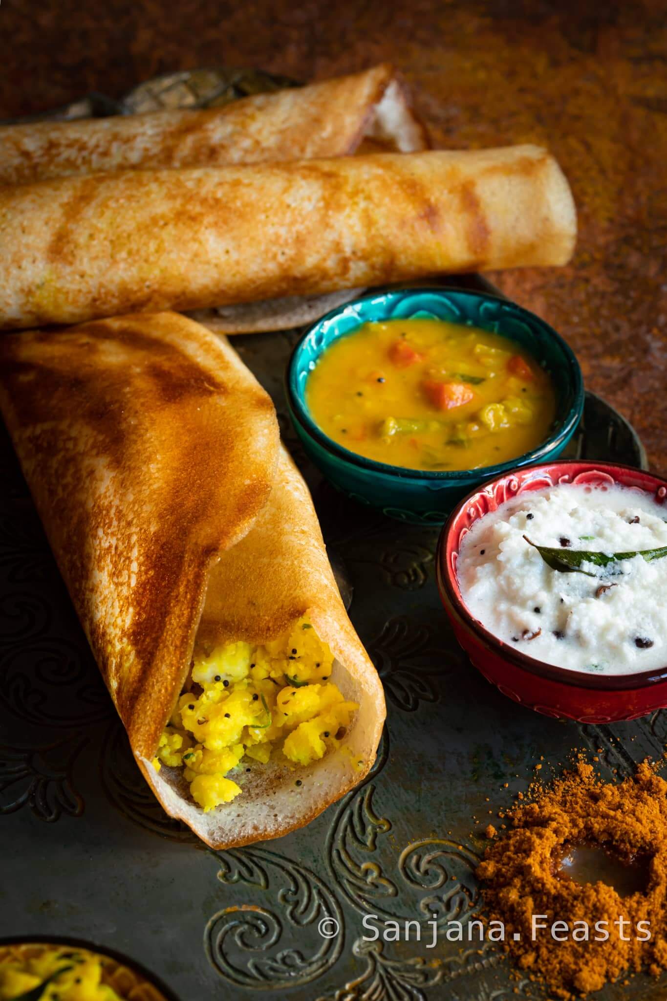 A platter of Indian breakfast masala dosa with coconut chutney and sambar in bowls
